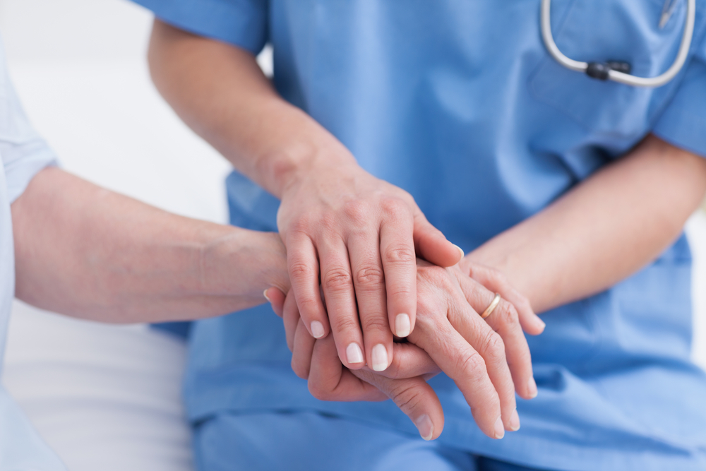 Close up of a nurse touching hand of a patient in hospital ward-1